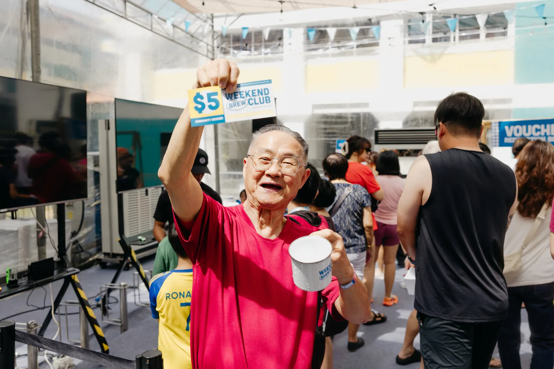 Weekend Brew Club attendee holding a branded enamel mug and community voucher